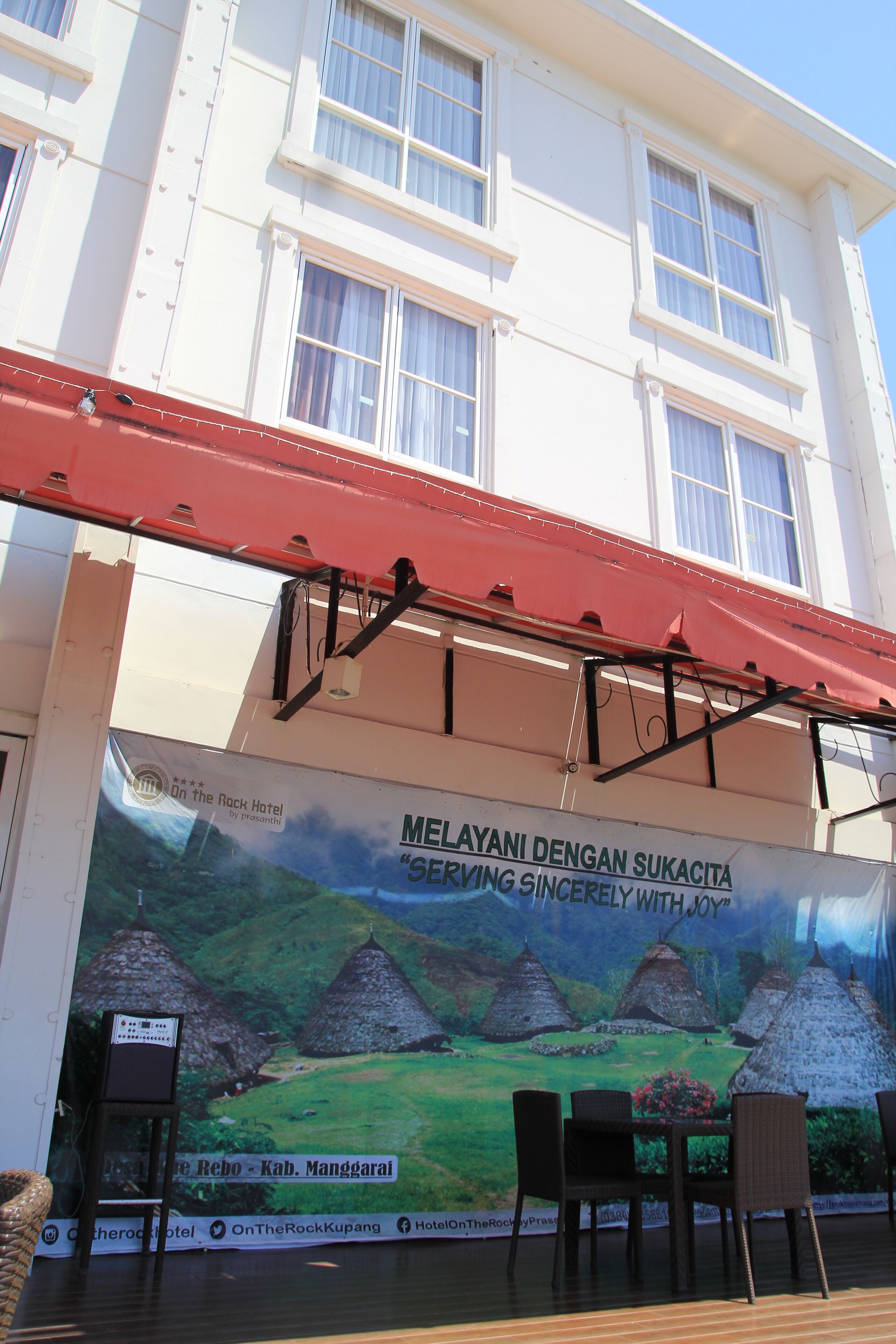 A hotel with a large mural of a rural landscape and a red awning.