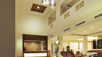 A hotel lobby with a reception desk, seating area, and a large screen.