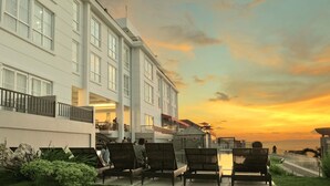 A hotel with a balcony and lounge chairs overlooking a sunset. - Hotel On The Rock (Kupang)