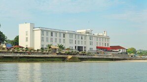 A large white building with multiple floors, a balcony, and a red roof. - Hotel On The Rock (Kupang)
