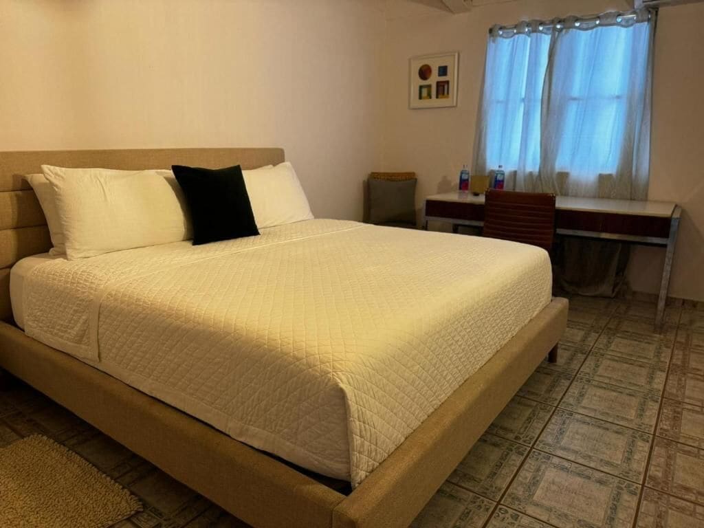 A hotel room with a large bed, a desk, and a chair.