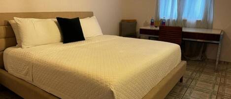 A hotel room with a large bed, a desk, and a chair.