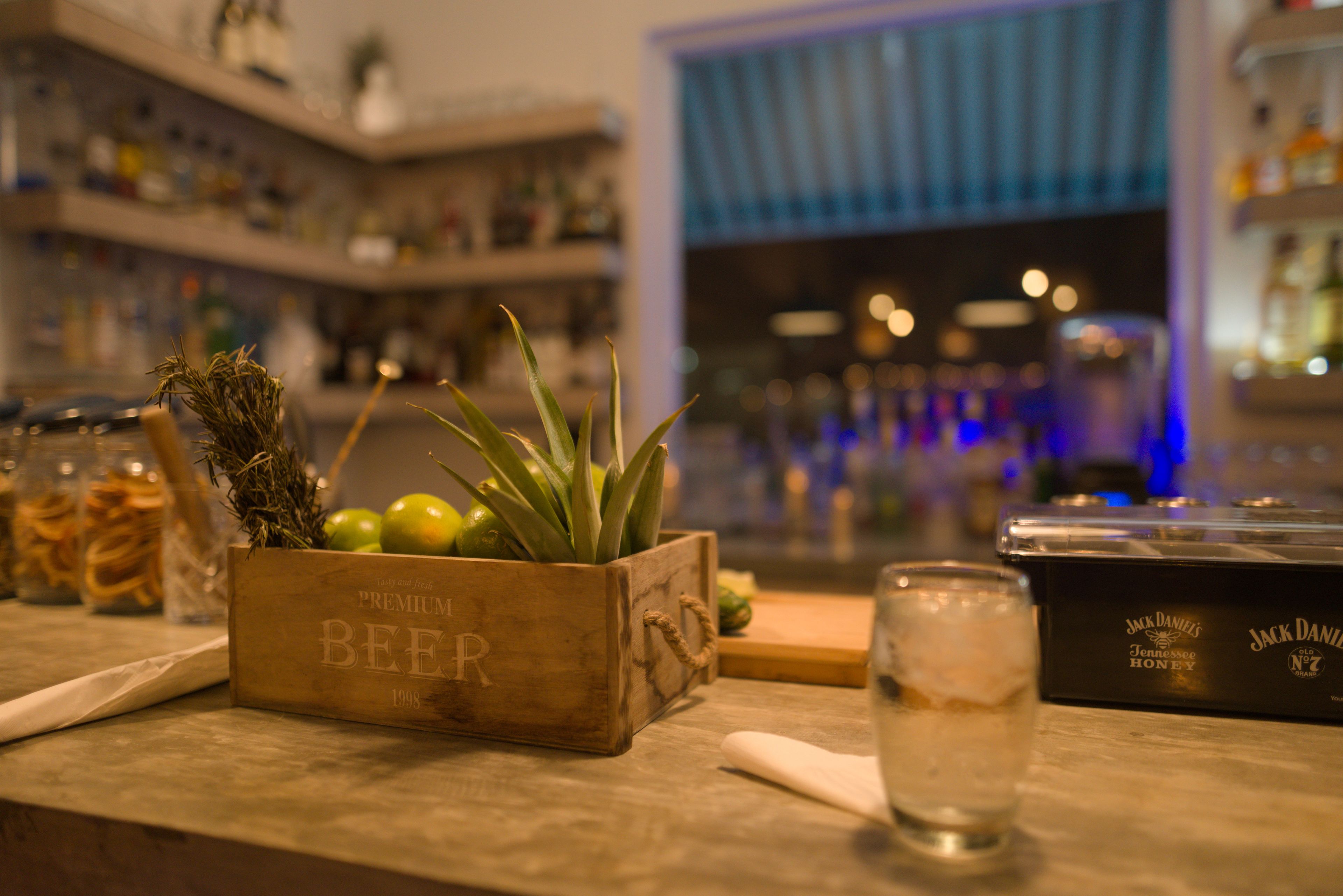 A bar area with a wooden box labeled "Premium Beer" and a glass of whiskey.