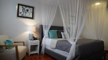 Une chambre à coucher comprenant un lit, une table de chevet, une chaise et une œuvre d’art accrochée au mur.