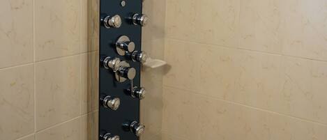 A shower with multiple controls and a handheld showerhead.