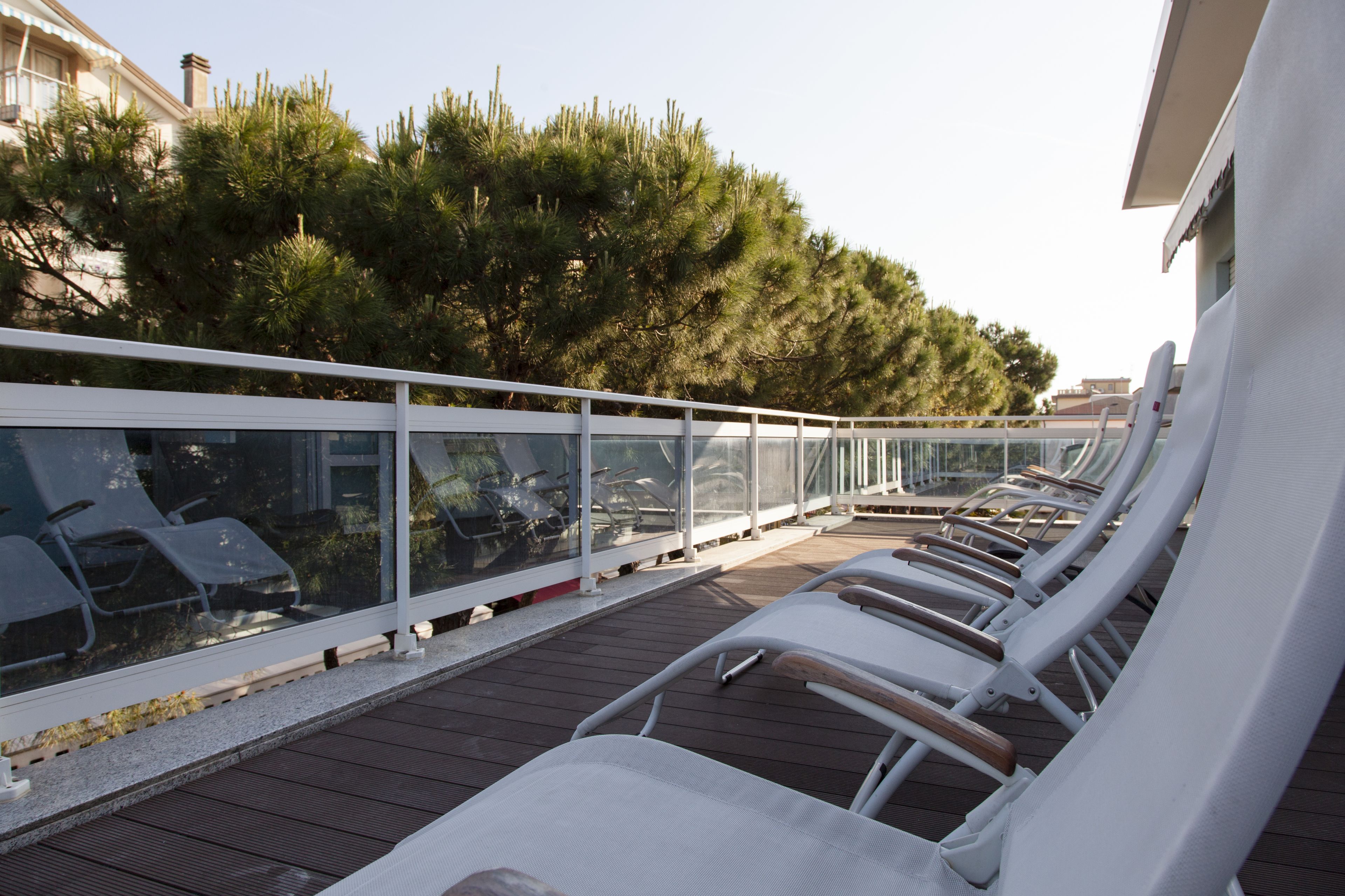 Terraza con sillones blancos y baranda de cristal.