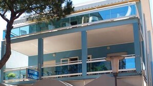 A two-story hotel with a glass facade, outdoor seating area, and a sign indicating it is a hotel bar. - Hotel Mare Live (Jesolo)