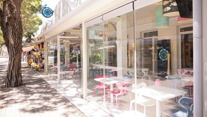 A cafe with outdoor seating, glass walls, and a tree nearby. - Hotel Mare Live (Jesolo)