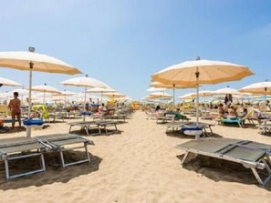 Uma praia com fileiras de espreguiçadeiras e guarda-sóis.