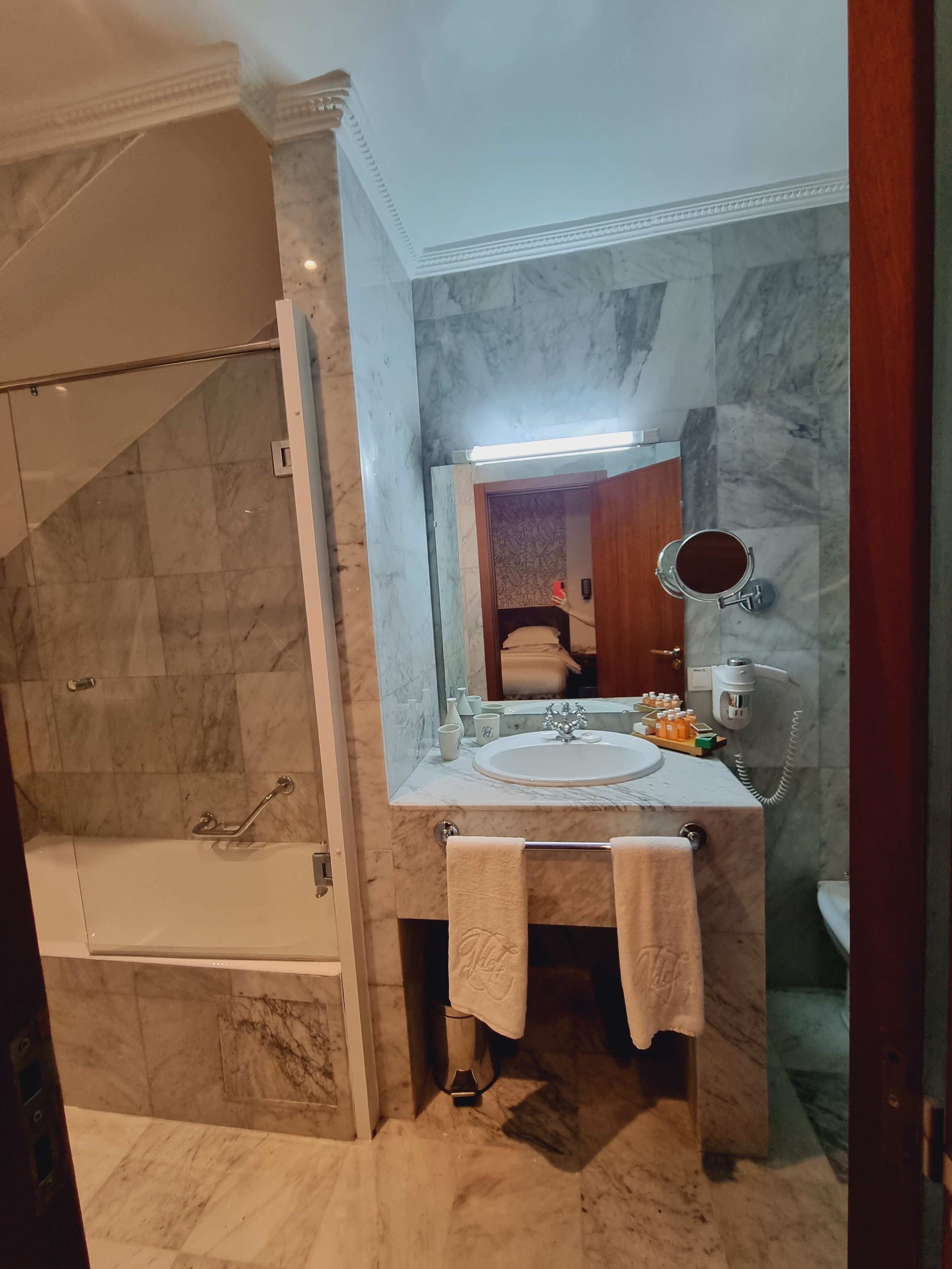 Een badkamer met een marmeren wastafel, een badkuip en een douche.
