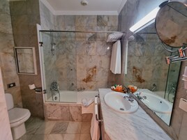 Un baño con ducha de vidrio, lavabo con espejo e inodoro.