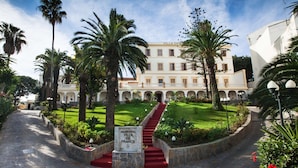 Ein prachtvolles Hotel mit Innenhof, einer roten Teppichstiege und üppiger Bepflanzung.