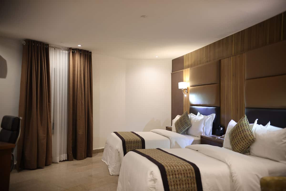 Une chambre d’hôtel avec deux lits, un bureau et une chaise.