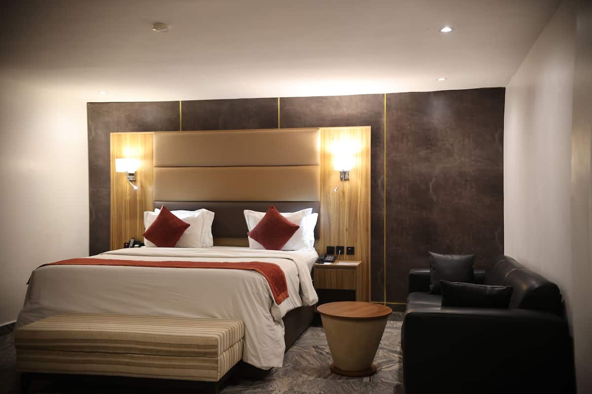Une chambre d’hôtel avec un grand lit, des tables de chevet, un canapé et une petite table ronde.