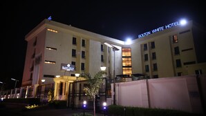 Un hôtel avec une enseigne bien visible indiquant « BOLTON WHITE HOTEL » et une entrée bien éclairée.