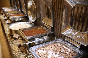 Enjoy a variety of dishes at our buffet, featuring multiple self-service stations with labeled trays.