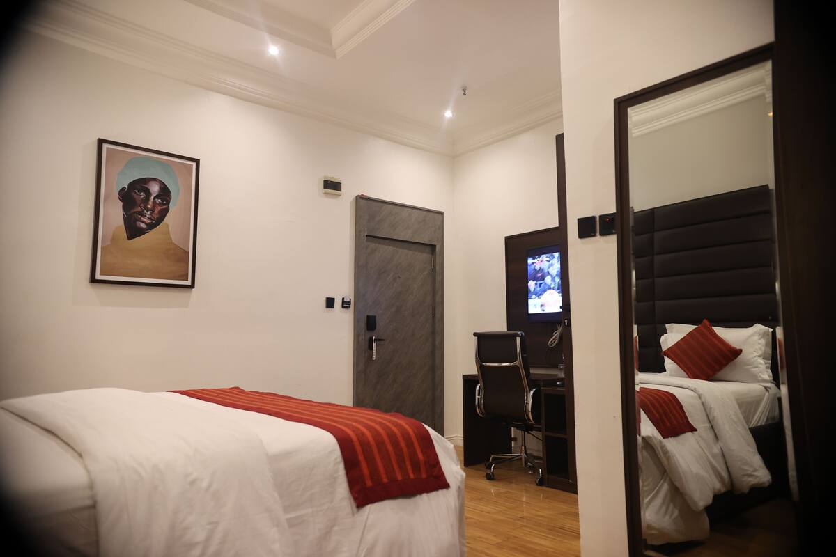 Une chambre d’hôtel avec deux lits, un bureau, une télévision et un tableau au mur.