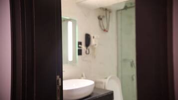 Une salle de bain avec un lavabo blanc, un miroir et un espace douche.