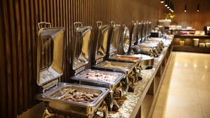 Un buffet proposant une variété de plats présentés dans des récipients en métal, le tout installé devant un mur en bois et sur un plancher ciré.