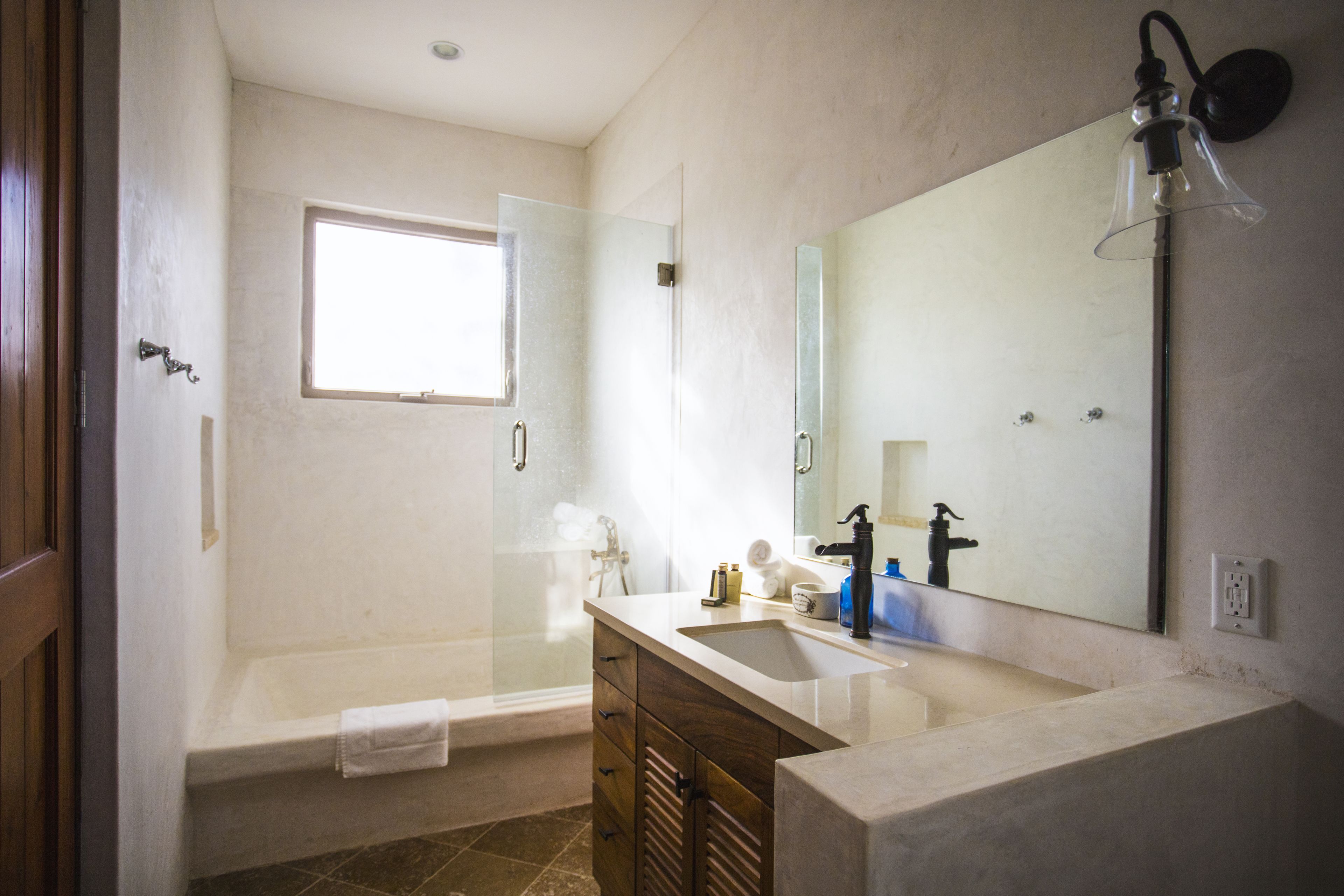 Un bagno con una vasca, un lavandino, uno specchio e una finestra.