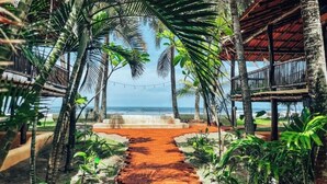 A tropical pathway leading to a beach with palm trees and a wooden structure. - Hotel El Sitio Playa Venao (Las Escobas del Venado)