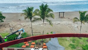 A beach view with palm trees, a sandy shore, and a construction vehicle in the background. - Hotel El Sitio Playa Venao (Las Escobas del Venado)