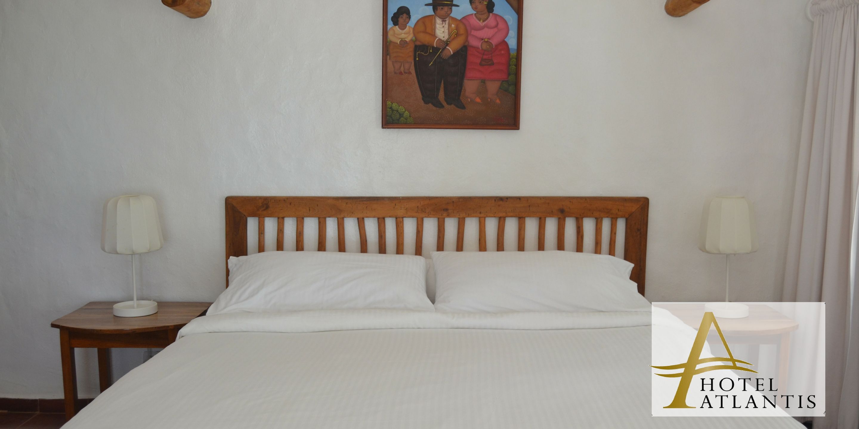 Ein Hotelzimmer mit einem Holzkopfteil, weißer Bettwäsche, zwei Nachttischlampen und einem Bild an der Wand.