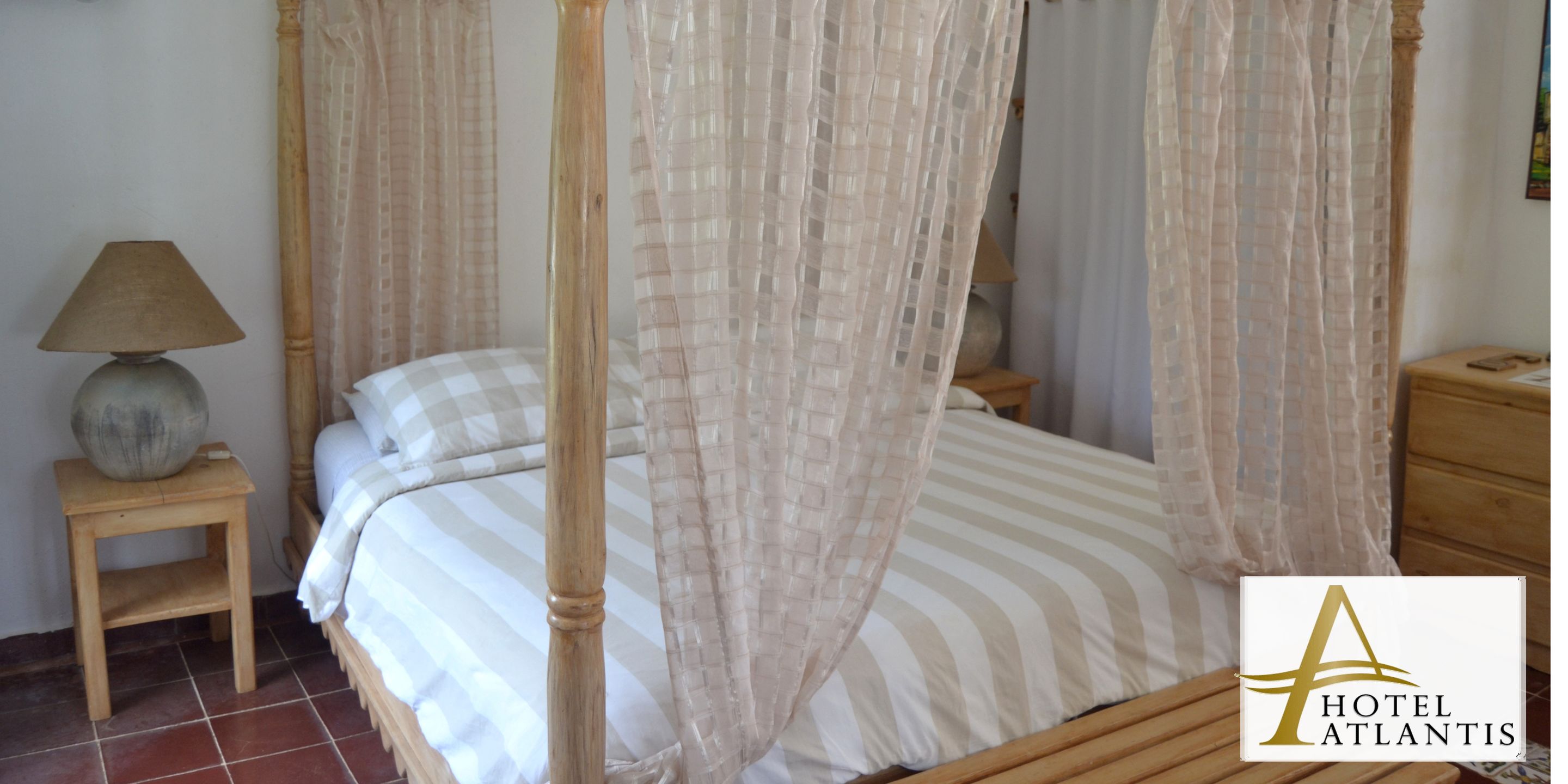 A four-poster bed with a canopy, a bedside table with a lamp, and a wooden nightstand.