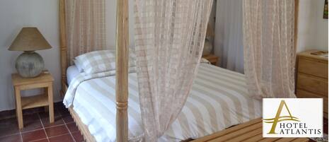 A four-poster bed with a canopy, a bedside table with a lamp, and a wooden nightstand.