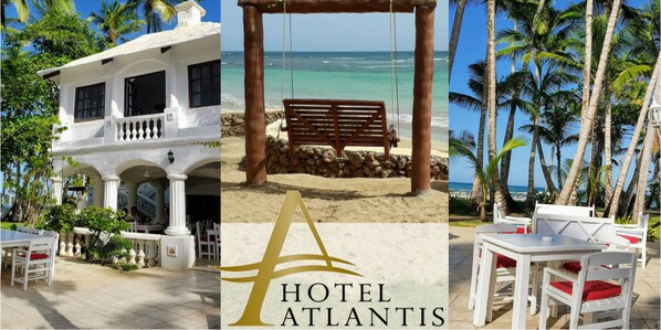 Un edificio blanco con balcón, una playa con una hamaca y vistas a palmeras.