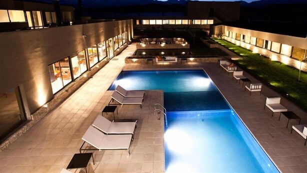A pool area with lounge chairs and a view of mountains at dusk. - Auberge Du Vin, Tupungato, Mendoza (Tupungato)
