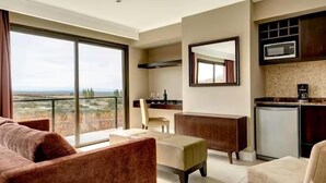 A modern living room with a sofa, a coffee table, and a dining area with a chair and a small table. There is a kitchen area with a microwave and a refrigerator. - Auberge Du Vin, Tupungato, Mendoza (Tupungato)