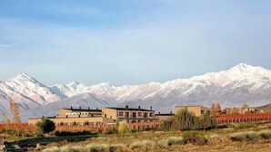A modern building with a flat roof, surrounded by a landscaped area with trees and shrubs. - Auberge Du Vin, Tupungato, Mendoza (Tupungato)