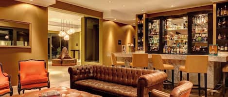 A bar area with leather seating, a bar counter, and shelves of liquor bottles.