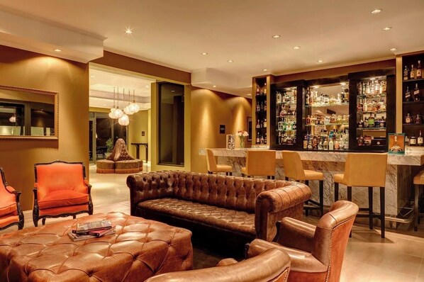 A bar area with leather seating, a bar counter, and shelves of liquor bottles.