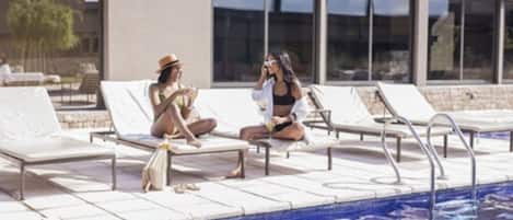 Un área junto a la piscina con sillones de descanso y una pileta.
