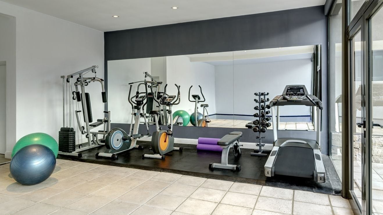 A gym with exercise equipment, a mirror, and a window.