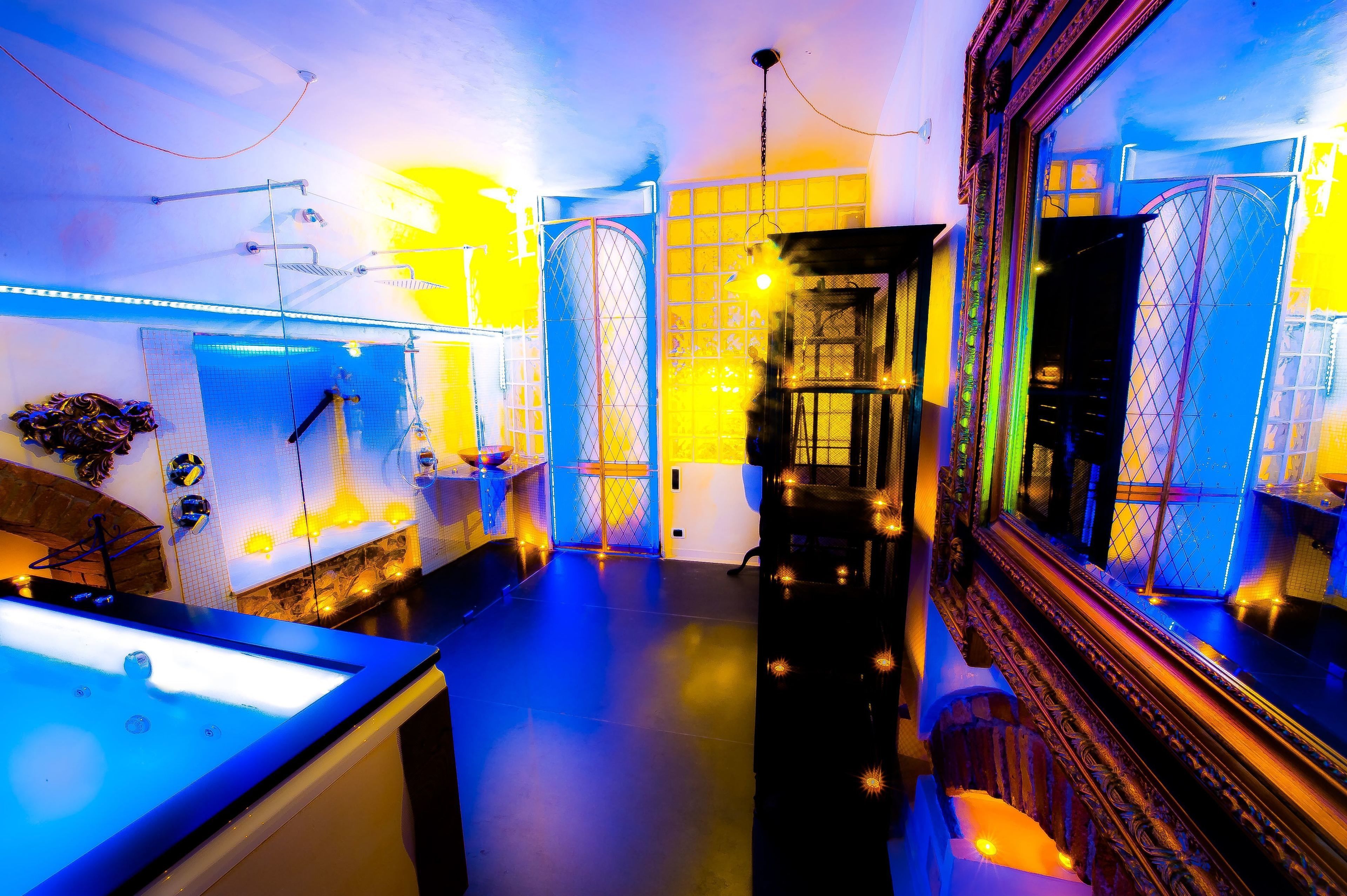 Un hall d’hôtel moderne avec un comptoir d’accueil central, un grand miroir et un escalier menant aux étages supérieurs.