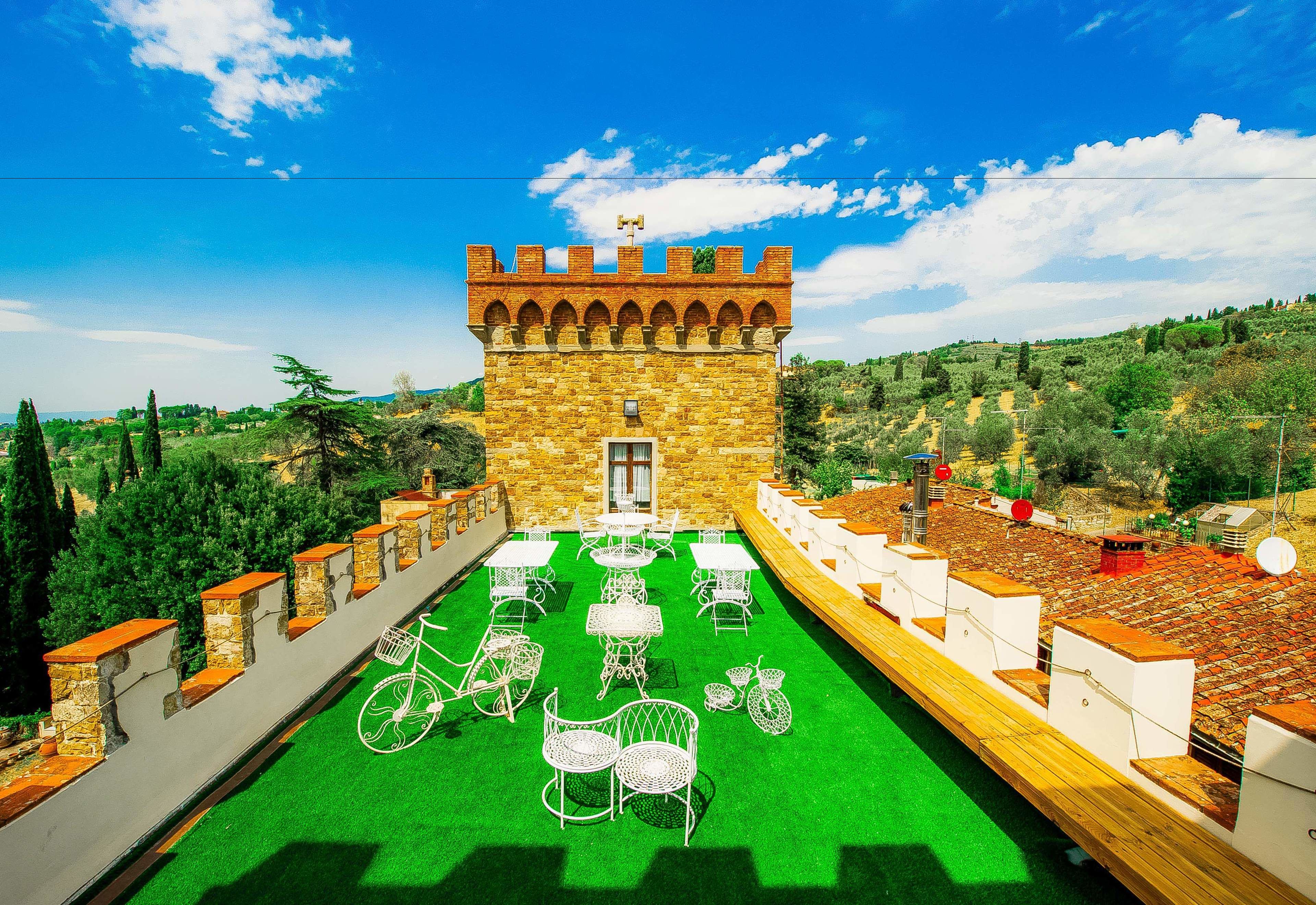 A courtyard with a stone tower, green artificial turf, and white metal furniture.