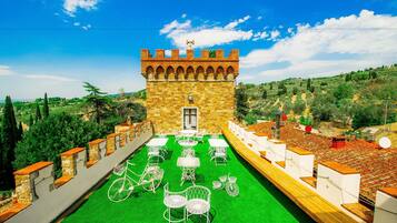 A courtyard with a stone tower, green artificial turf, and white metal furniture.