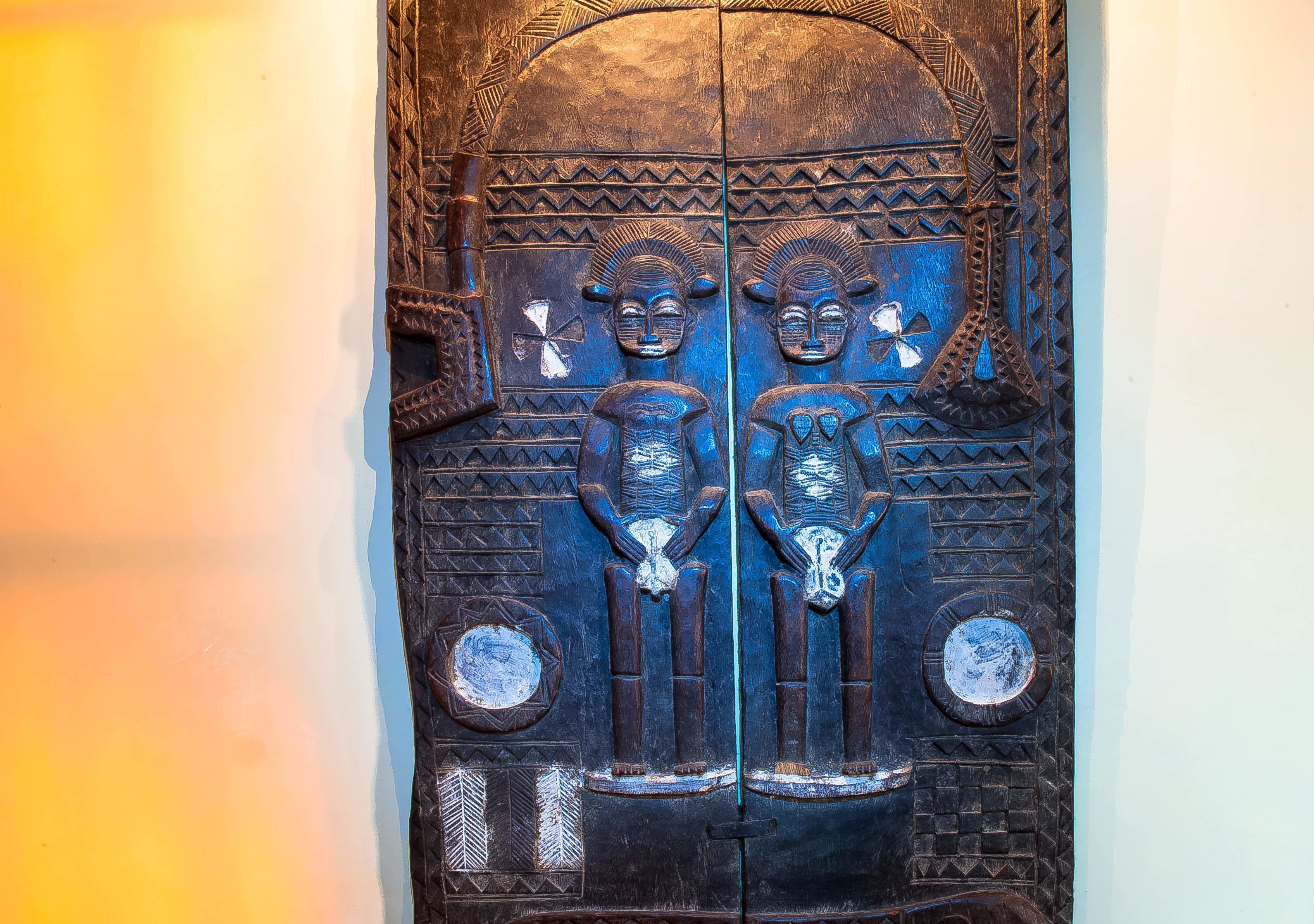 Une porte en bois ornée de sculptures complexes et de deux médaillons circulaires.