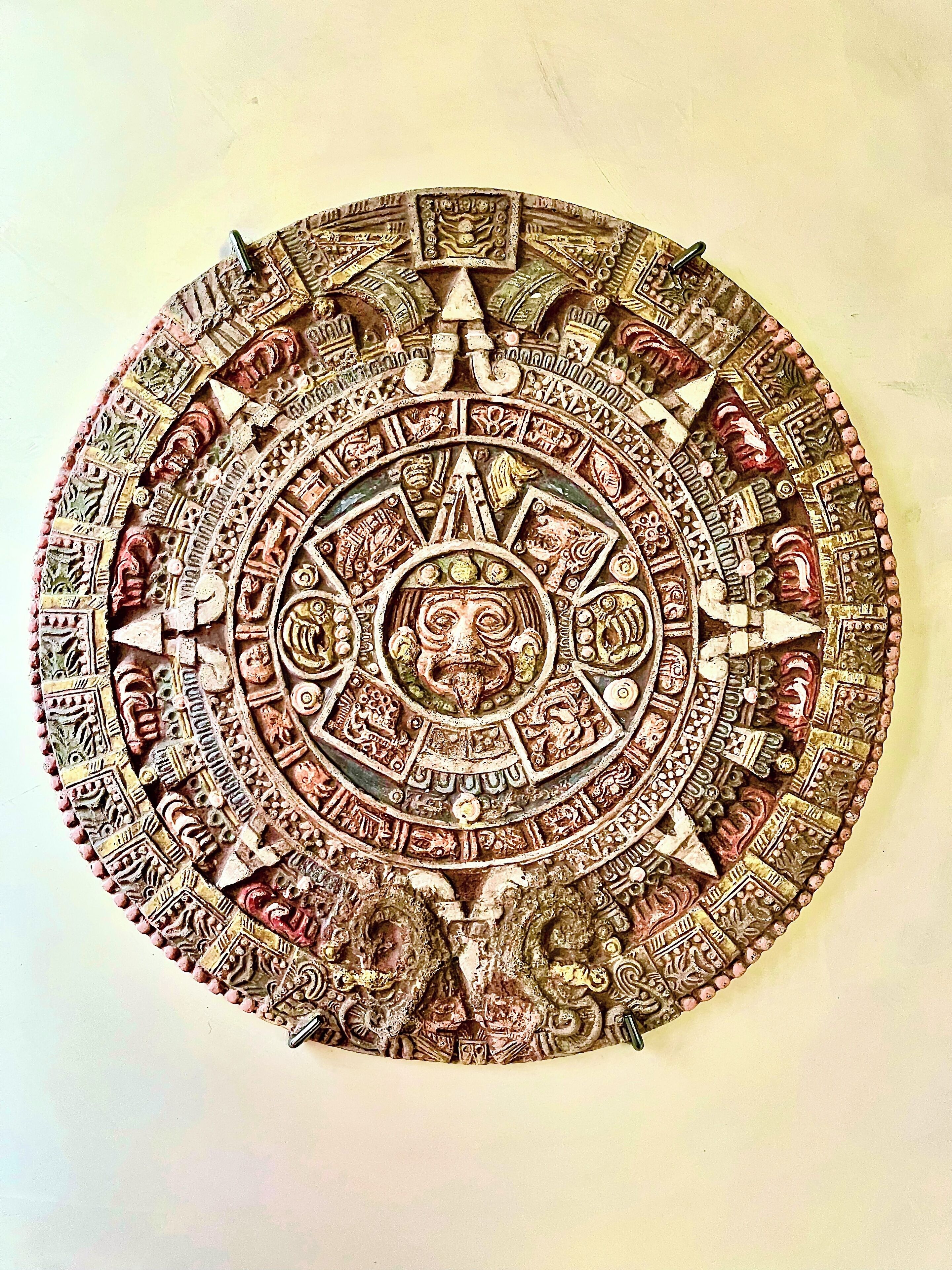A circular artifact with intricate carvings and symbols, featuring a central figure and surrounding motifs.