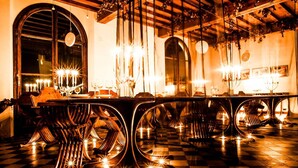 A long dining table with multiple candle chandeliers, wooden chairs, and checkered flooring. - Castello di Montalbano (Florence)