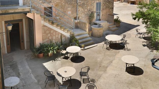 Un patio con edificios de piedra, mobiliario exterior y una escalera.