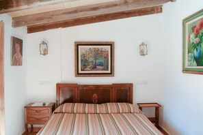 Una camera da letto con una testiera in legno, un letto con lenzuola a righe, due comodini e opere d'arte incorniciate alle pareti.