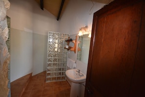 A bathroom with a tiled shower, a white sink, and a wooden door. - Agroturismo Finca Dalt Murada (Binissalem)