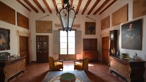 Una habitación amplia con vigas de madera, un ventanal grande y una mesa central con sillas.