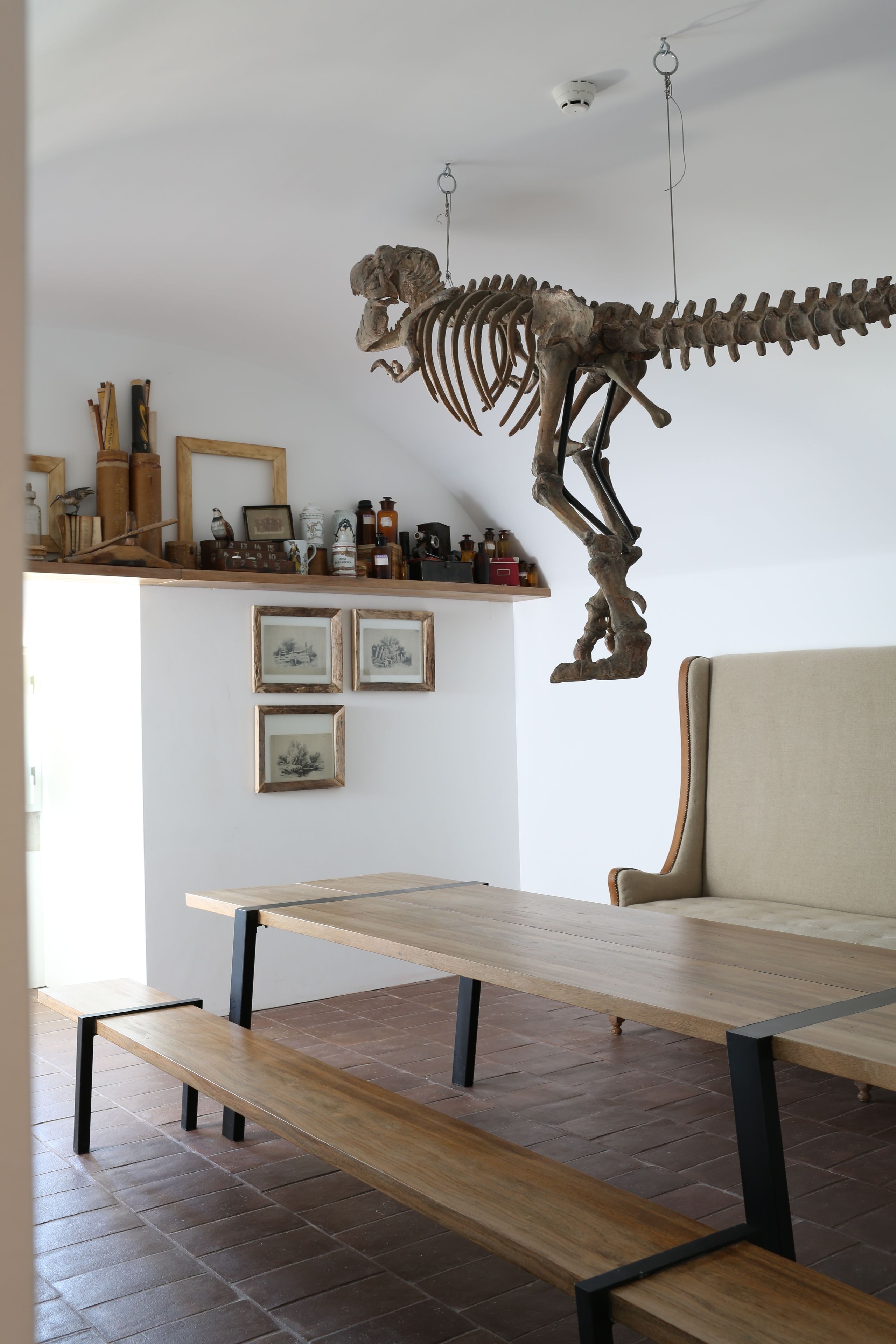 Ein Zimmer mit einer hölzernen Bank, einem Sofa und einem an der Wand befestigten Skelett.