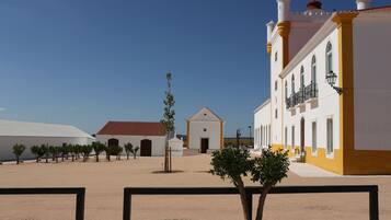 A courtyard with white buildings, a small church, and a tree.