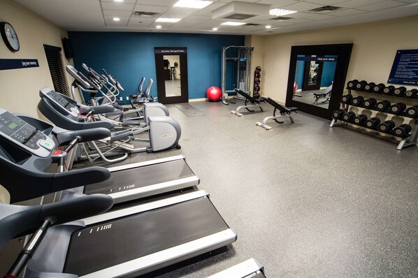 A gym with treadmills, a red exercise ball, and dumbbells.